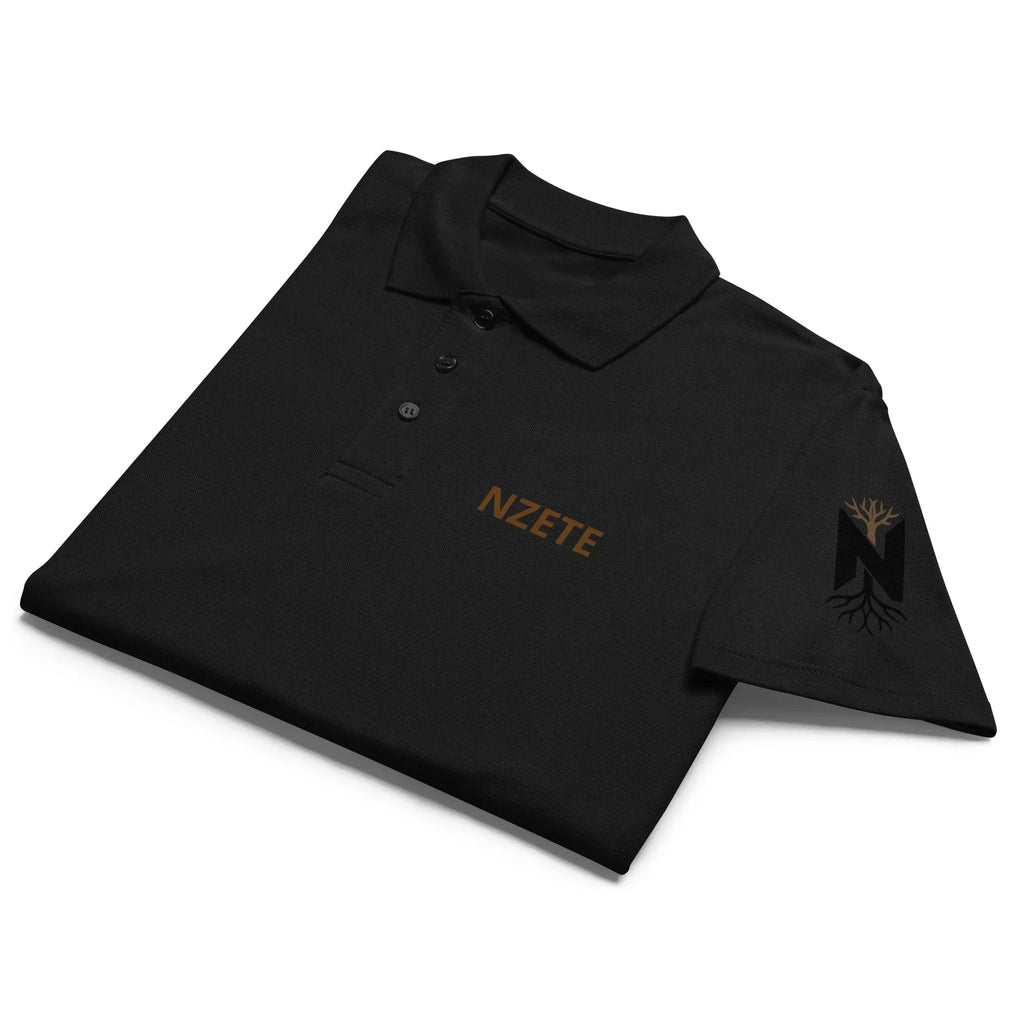 Black unisex premium polo shirt folded, gold NZETE logo on chest, tree graphic on sleeve